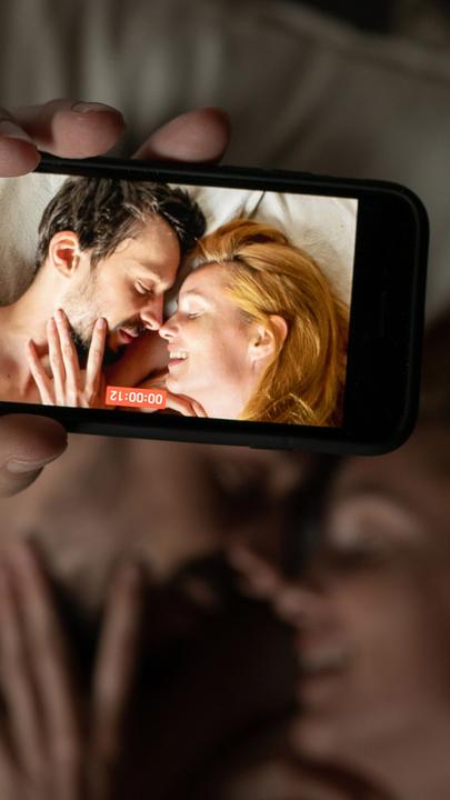 Petr (Matyás Reznícek) und Hana (Hana Vagnerová) liegen sich im Bett gegenüber, dabei, ein Selfie zu machen: Im Bildvordergrund sieht man sie scharf auf einem Handydisplay, im Bildhintergrund unscharf.