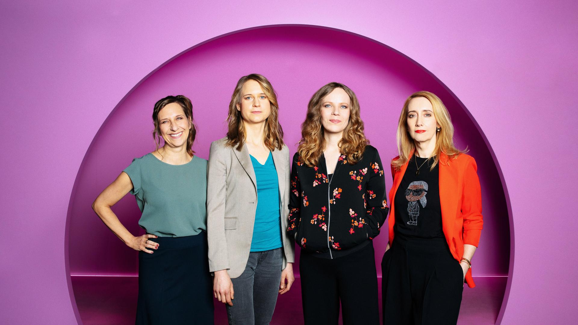 Auf dem Bild ist Sarah Bosetti als zweite von rechts zu sehen. Es sind vier Frauen auf dem Bild. Der Hintergrund ist rosa.