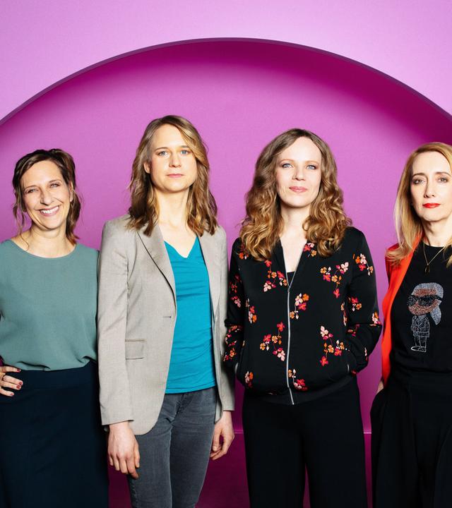 Auf dem Bild ist Sarah Bosetti als zweite von rechts zu sehen. Es sind vier Frauen auf dem Bild. Der Hintergrund ist rosa.