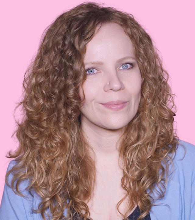 Sarah Bosetti befindet sich vor einem rosa Hintergrund. Rechts von ihr in einer Blase ist Donald Trump abgebildet.