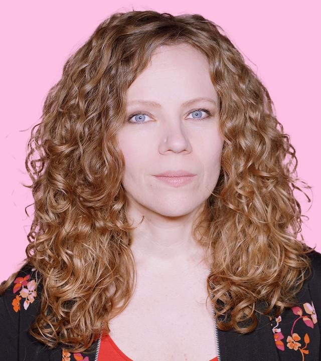 Sarah Bosetti befindet sich vor einem rosa Hintergrund. Rechts von ihr in einer Blase ist Donald Trump abgebildet.