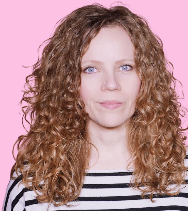 Sarah Bosetti befindet sich vor einem rosa Hintergrund. Rechts von ihr in einer Blase ist Wim Wenders abgebildet.