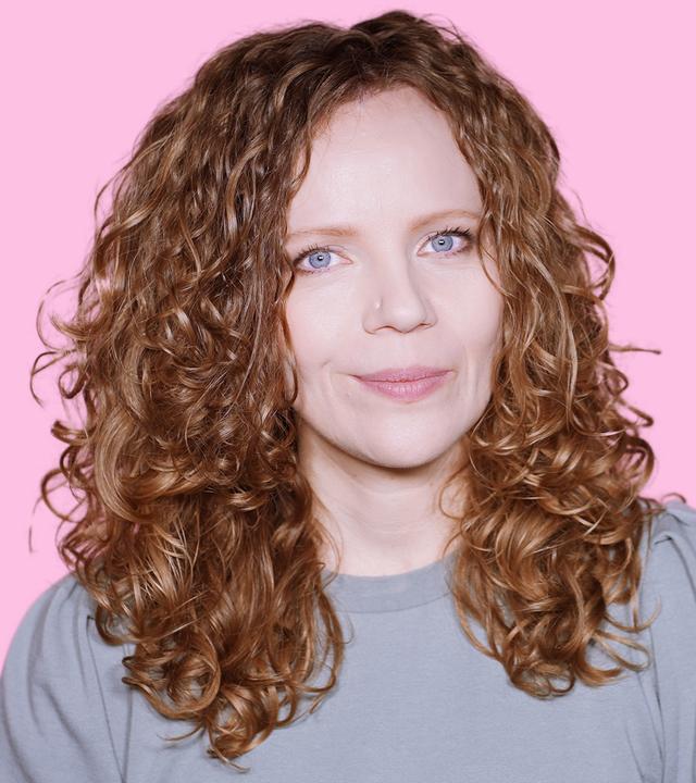 Sarah Bosetti befindet sich vor einem rosa Hintergrund. Rechts von ihr in einer Blase ist Friedrich Merz abgebildet.