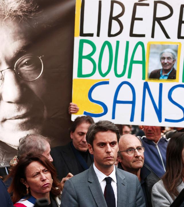 Menschen mit Plakaten stehen vor einem großen Bild des Schriftstellers.