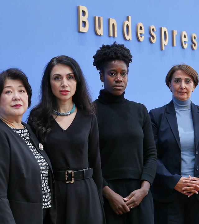 Vier Vetreterinnen von Migranten-Verbänden stehen vor der blauen Wand der Bundespressekonferenz.