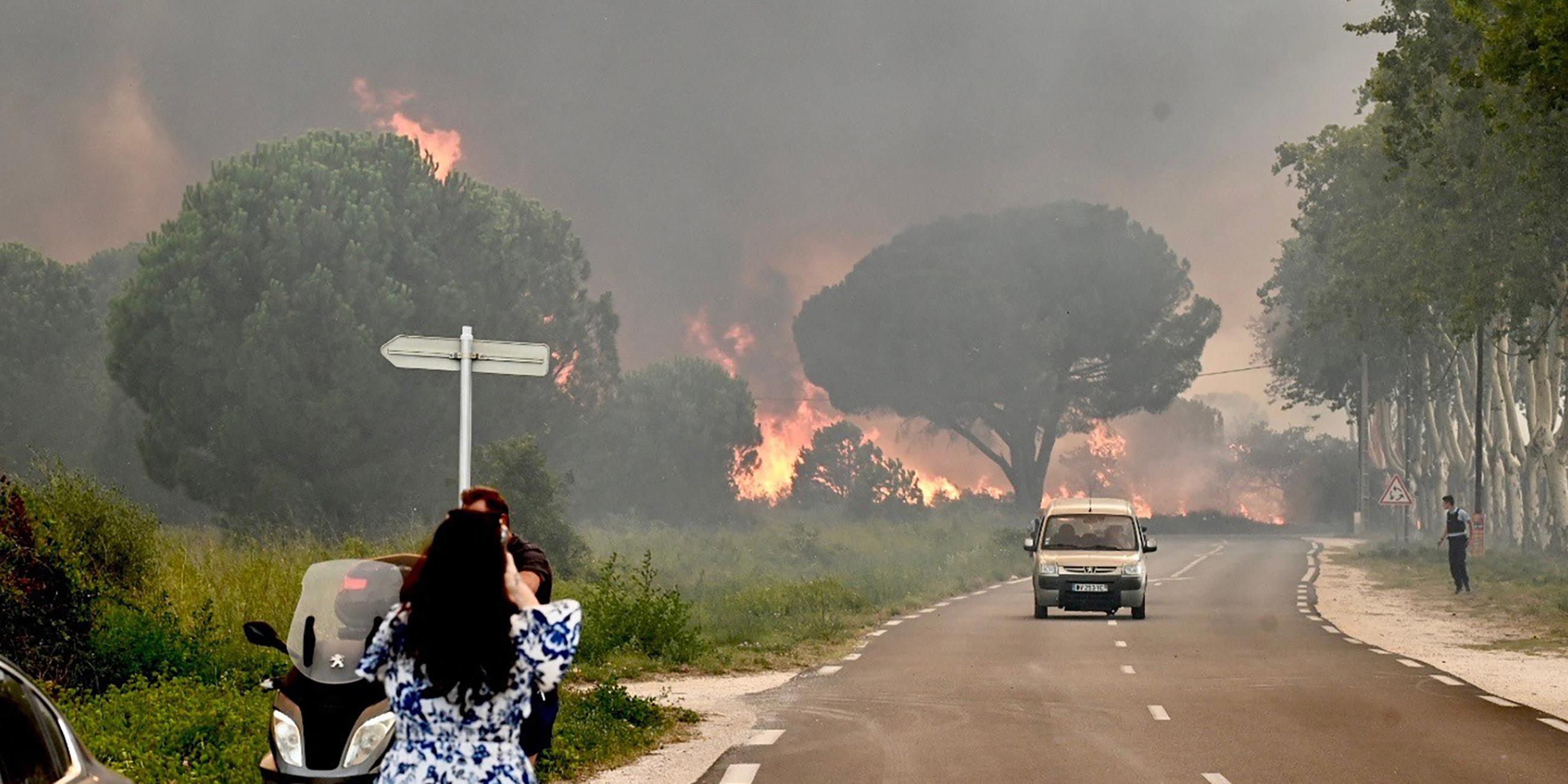 Eine Frau fotografiert am 14.08.2023 ein verheerendes Feuer im Südwesten Frankreichs.