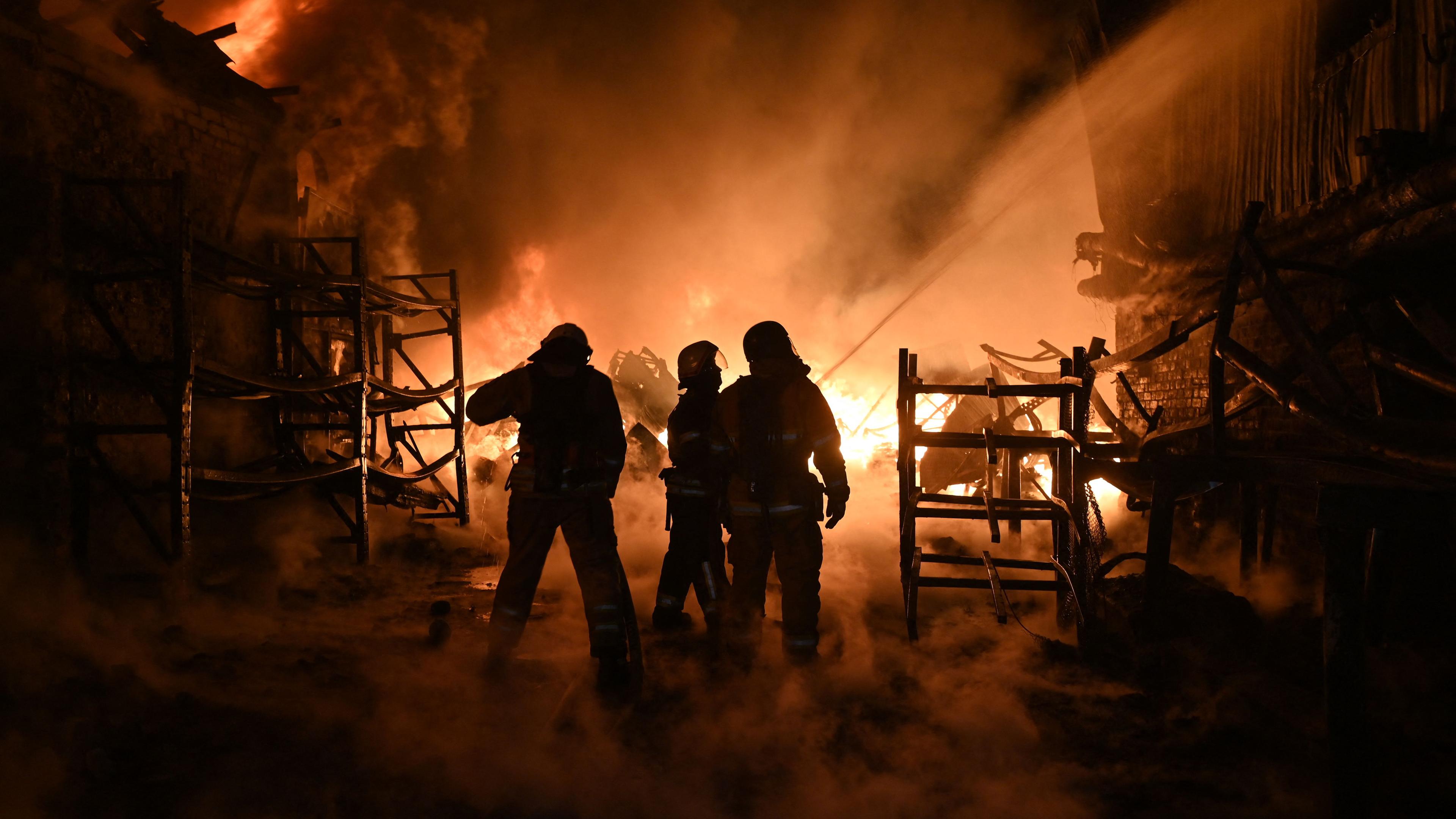 Ukrainische Feuerwehrleute löschen ein Feuer am Ort eines Drohnenangriffs auf Industrieanlagen in Charkiw am 04.05.2024