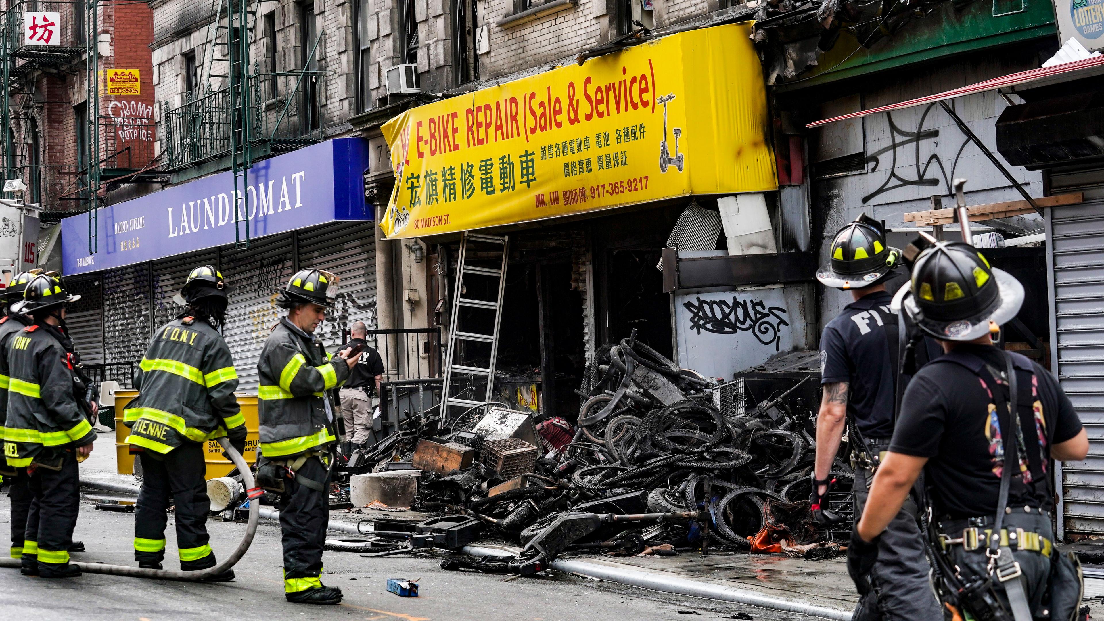 Feuerwehrleute und Ermittler stehen nach dem Brand eines Fahrradgeschäfts in New york