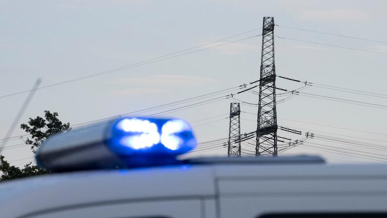 Ein Polizeiauto ist vor einer Hochspannungsleitung zu sehen. Heute waren am Umspannwerk in der Nähe unkonventionelle Sprengvorrichtungen gefunden worden.