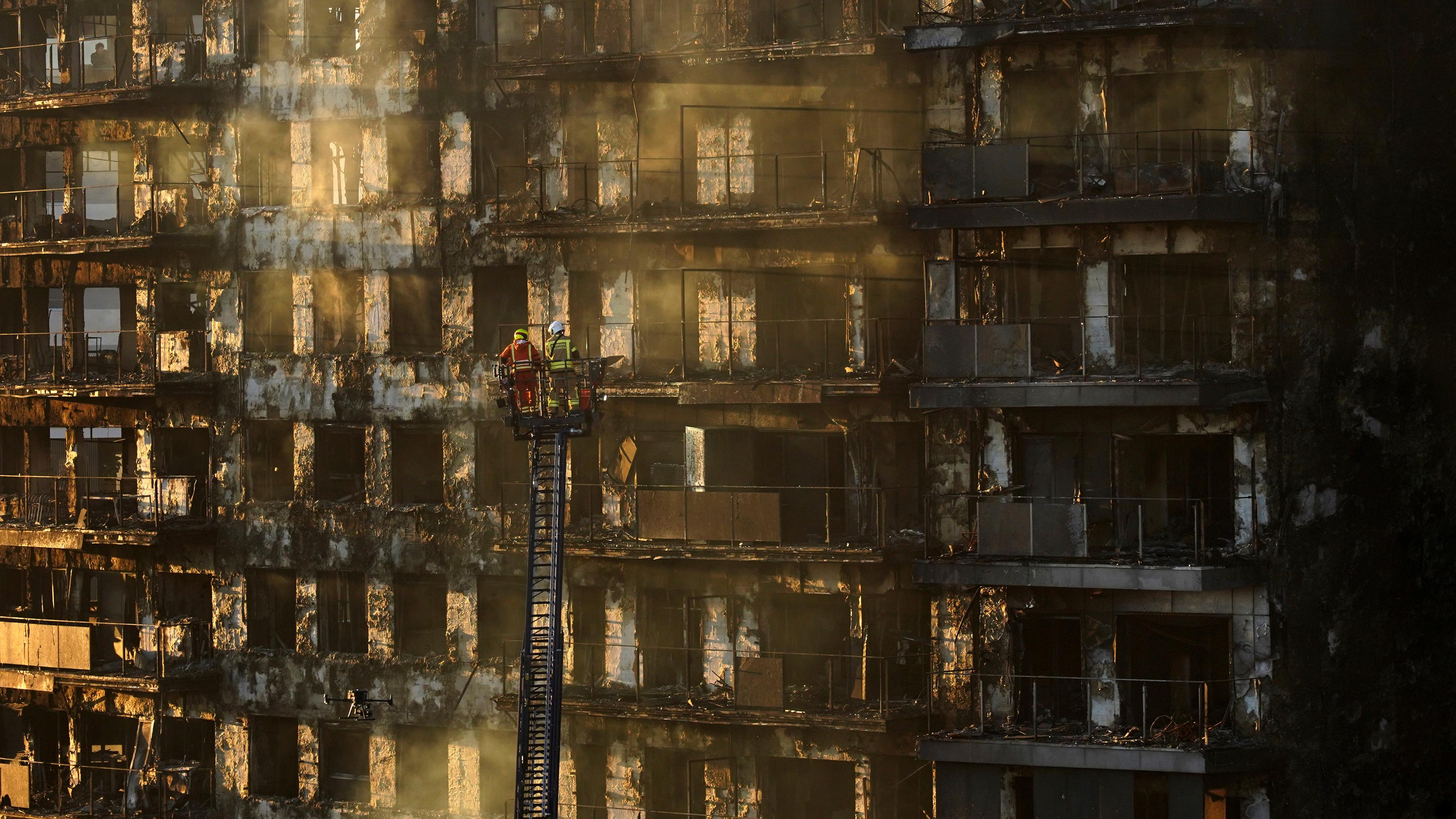 Firefighters work at a burned block building in Valencia, Spain, Friday, Feb. 23, 2024.