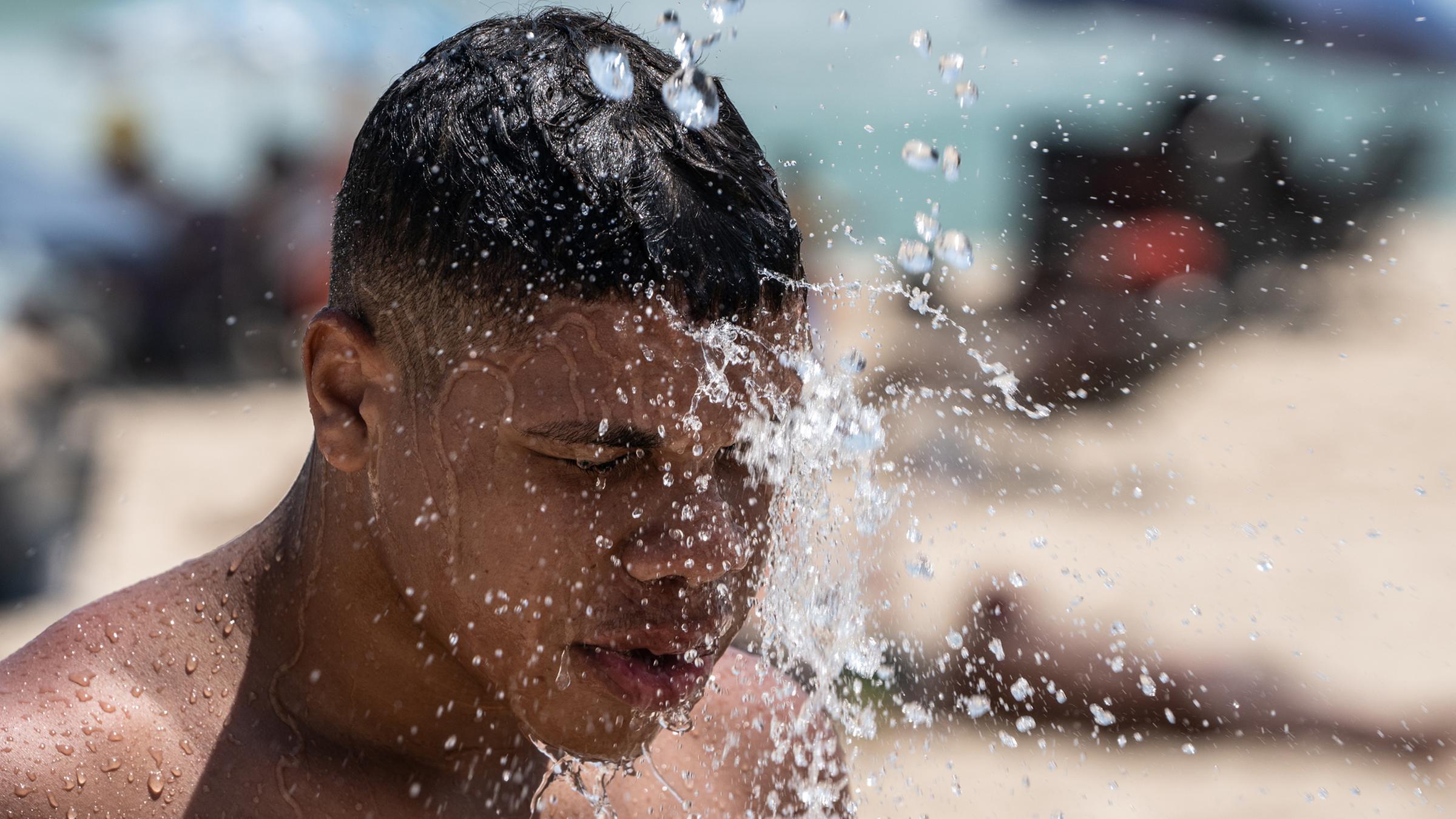  Ein Mann duscht am Strand von Ipanema
