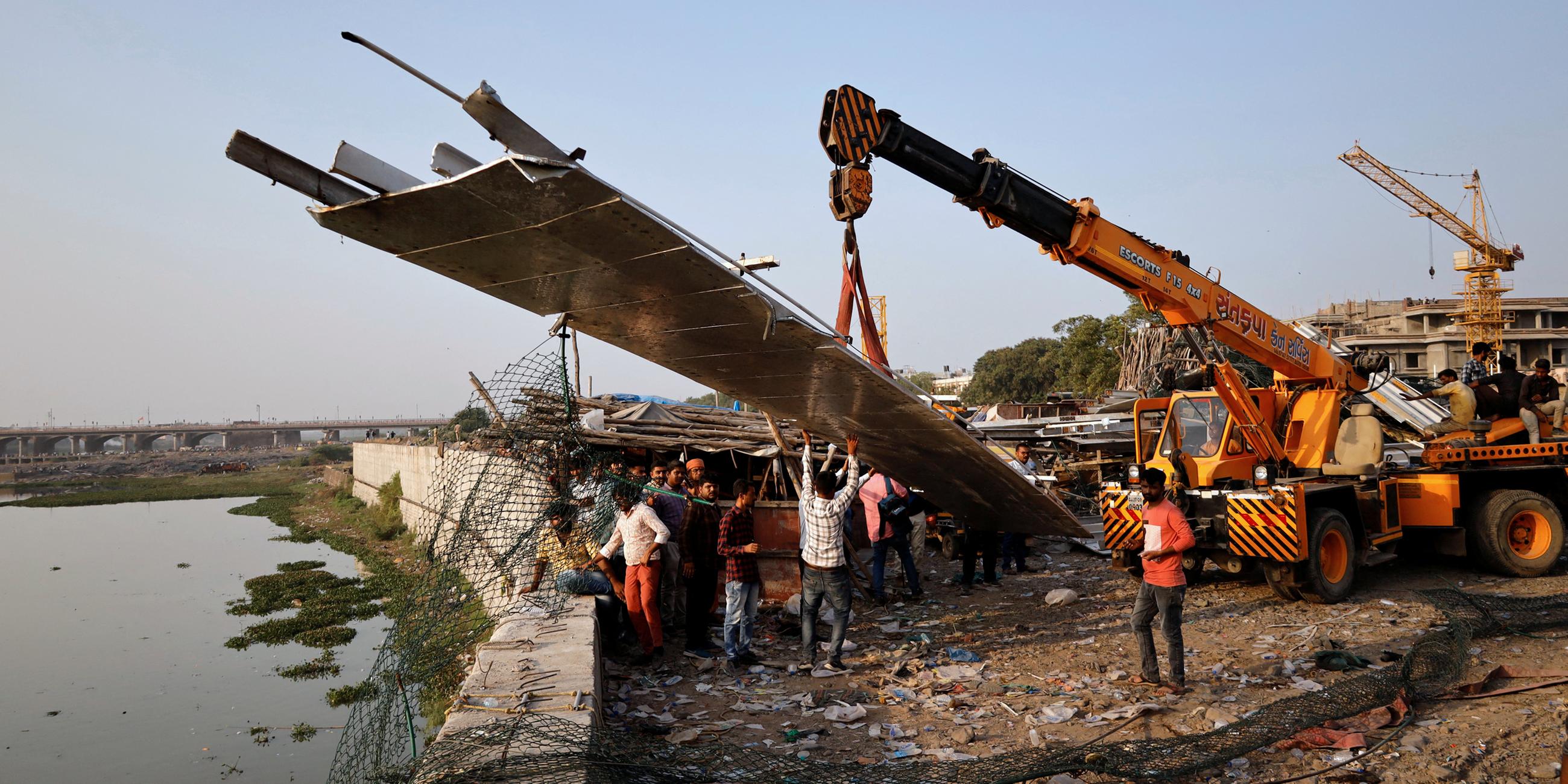Menschen entfernen Trümmer, nachdem eine Hängebrücke in der Stadt Morbi in Indien eingestürzt ist.