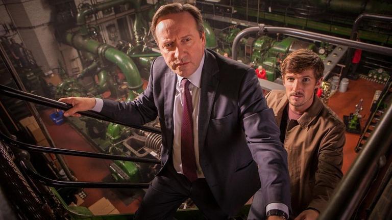 Barnaby (Neil Dudgeon, l.) und Nelson (Gwilym Lee, r.) durchsuchen die alte Keksfabrik nach Hinweisen auf den Mord.