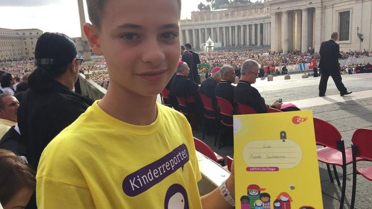 Kinderreporter Christian mit logo!-Buch in der ersten Reihe der Generalaudienz