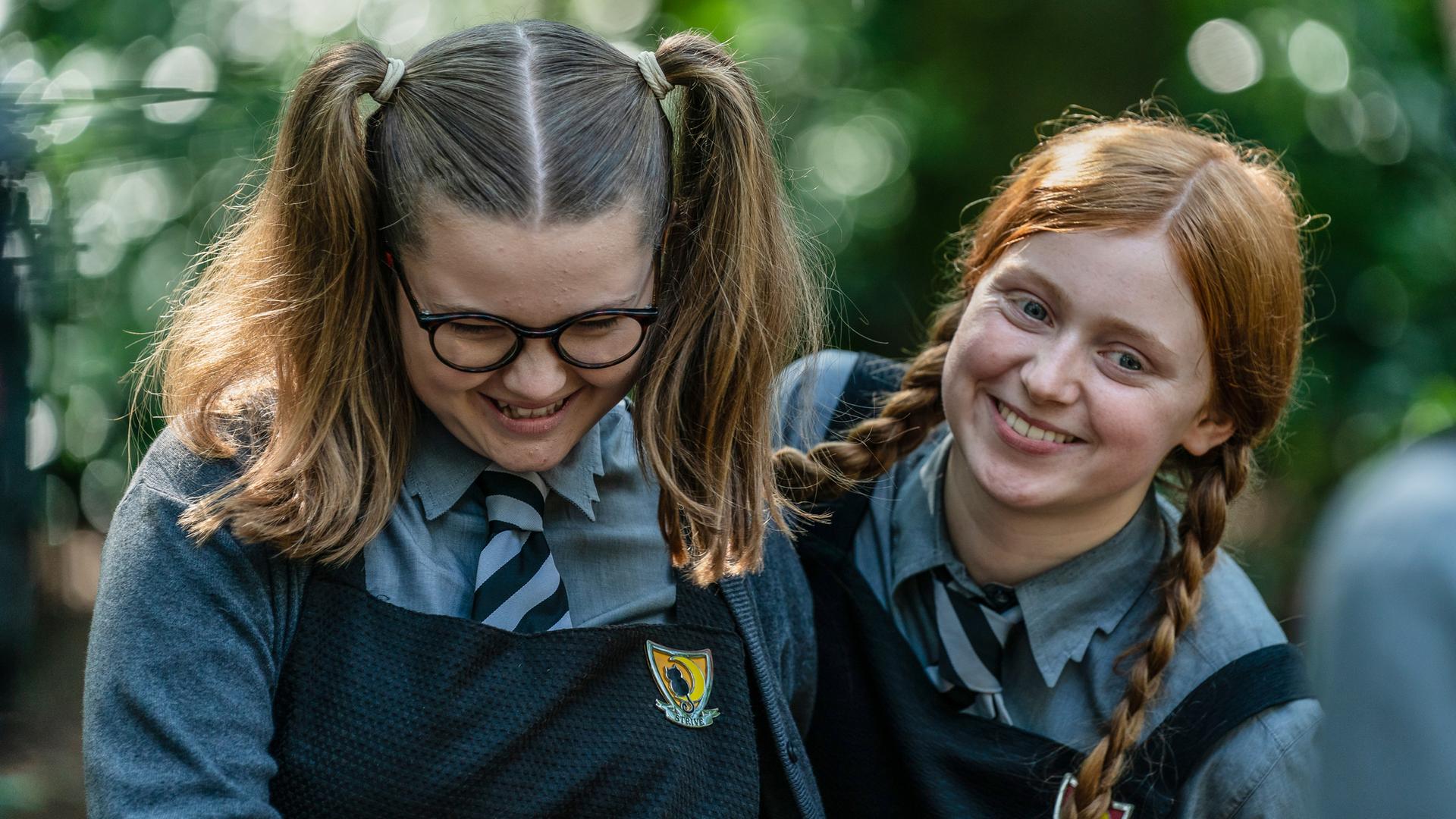 Mildred Hoppelt (Lydia Page, rechts), neben ihr steht Maude Mondschein (Meibh Campell, links) beide lachen