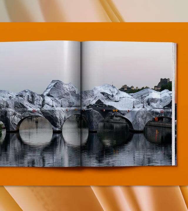 In einem aufgeschlagenen Buch ist ein Foto der verhüllten Pont Neuf Brücke in Paris zu sehen.