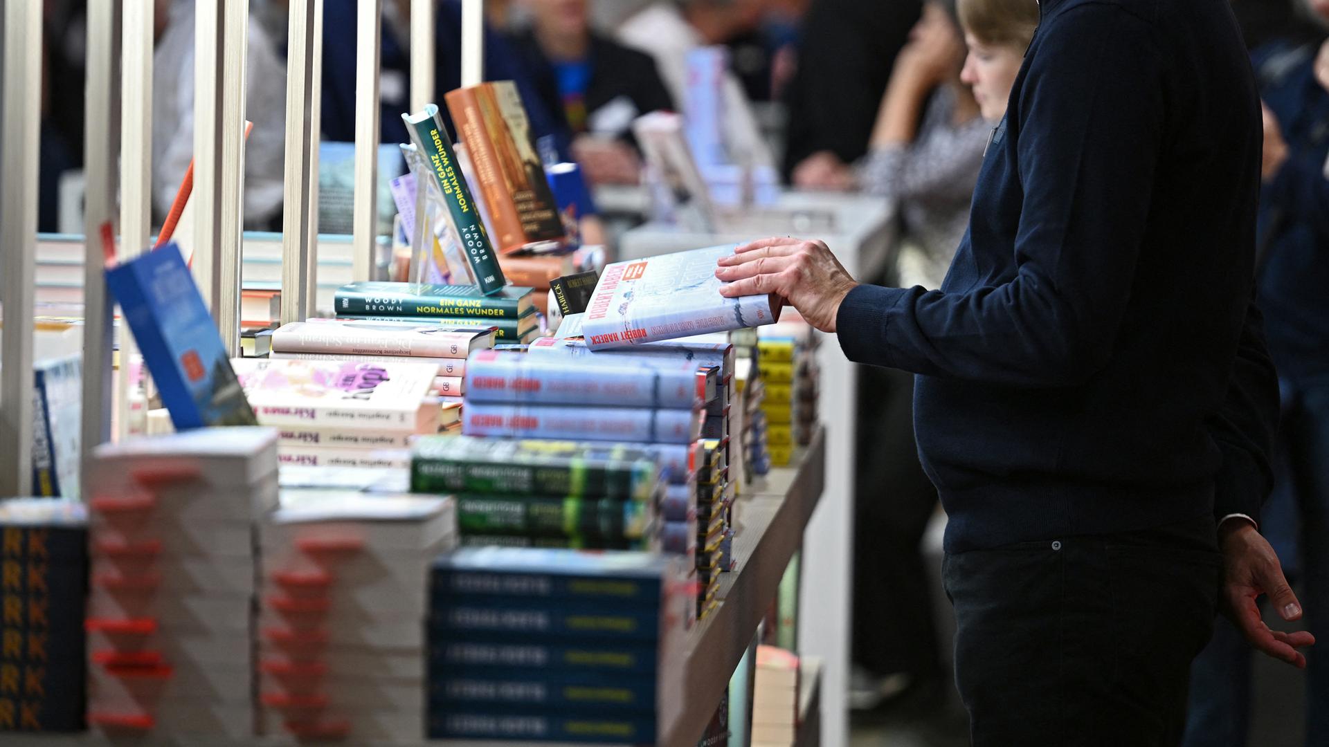 Um einen Büchertisch stehen mehrere Personen und schmökern.