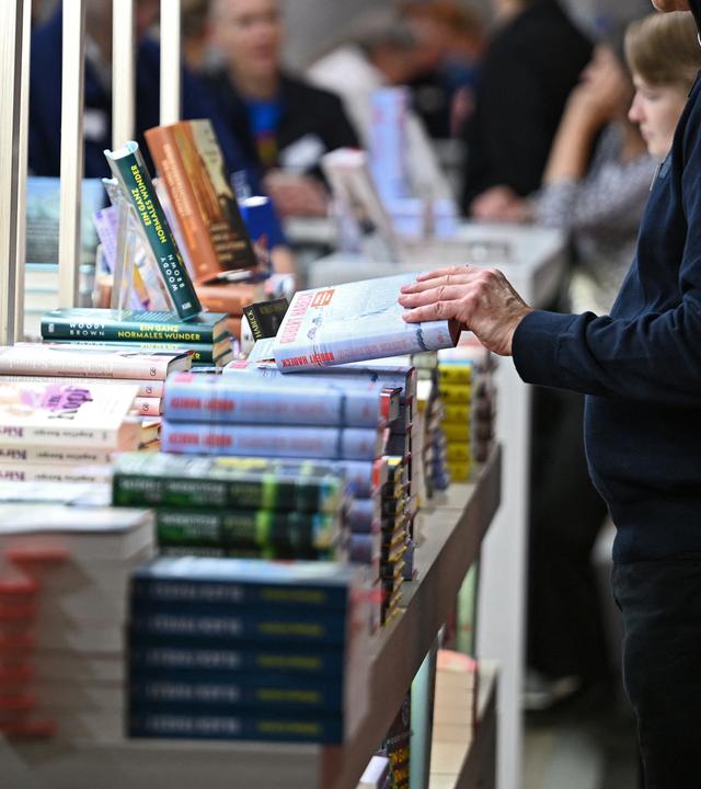 Um einen Büchertisch stehen mehrere Personen und schmökern.
