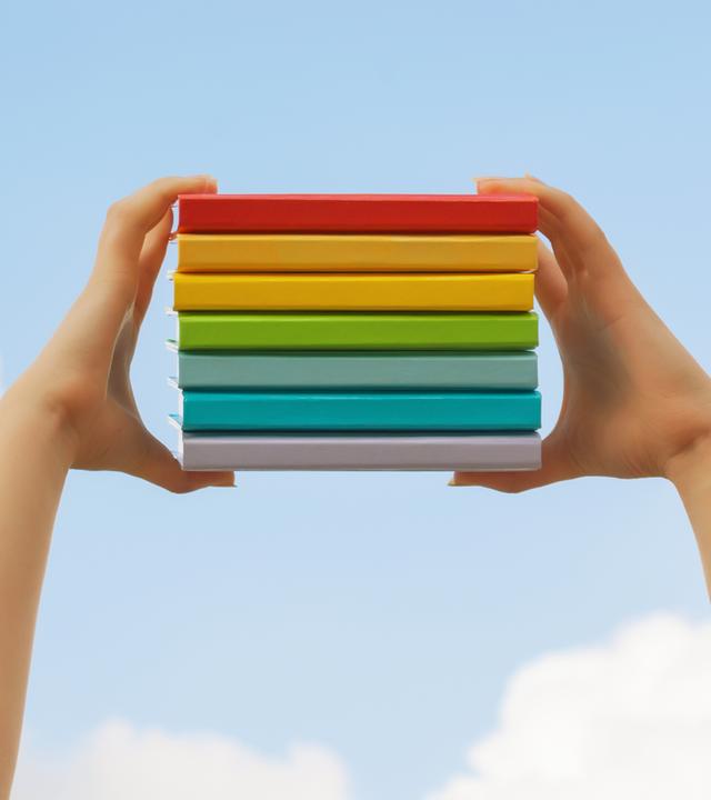 Bücherstapel zwischen zwei Händen in die Luft gehoben