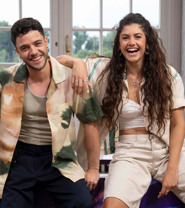 Ein junger Mann und eine junge Frau umarmen sich lachend.