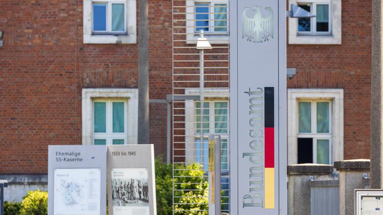 Eine Stele mit dem Bundesadler und der Aufschrift "Bundesamt" in den Farben der deutschen Flagge markiert den Eingang zu einer Behörde.