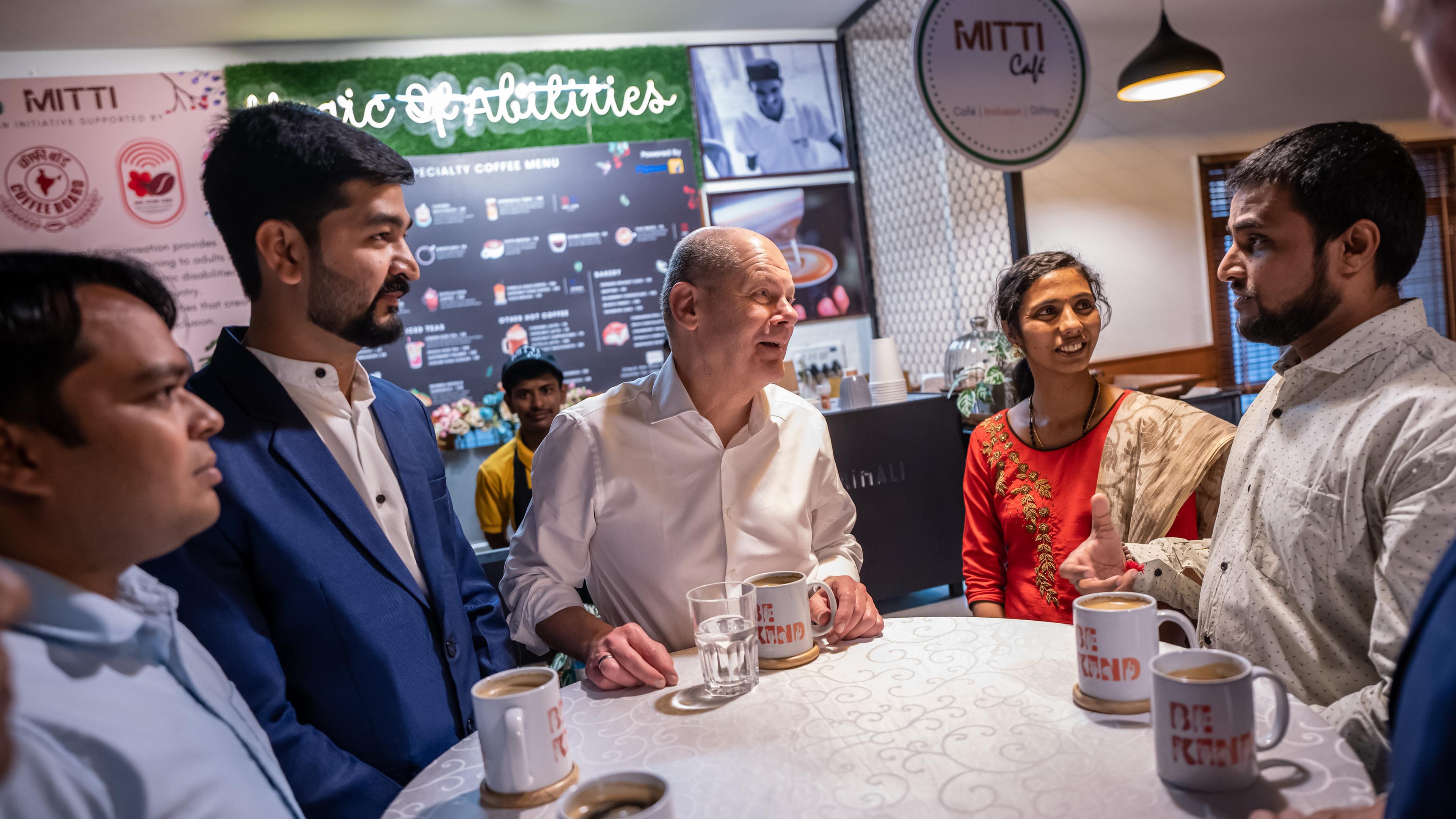 Indien, Bengaluru: Bundeskanzler Olaf Scholz (SPD) spricht im Matti Café mit Fachkräften, die vor der Ausreise nach Deutschland stehen.