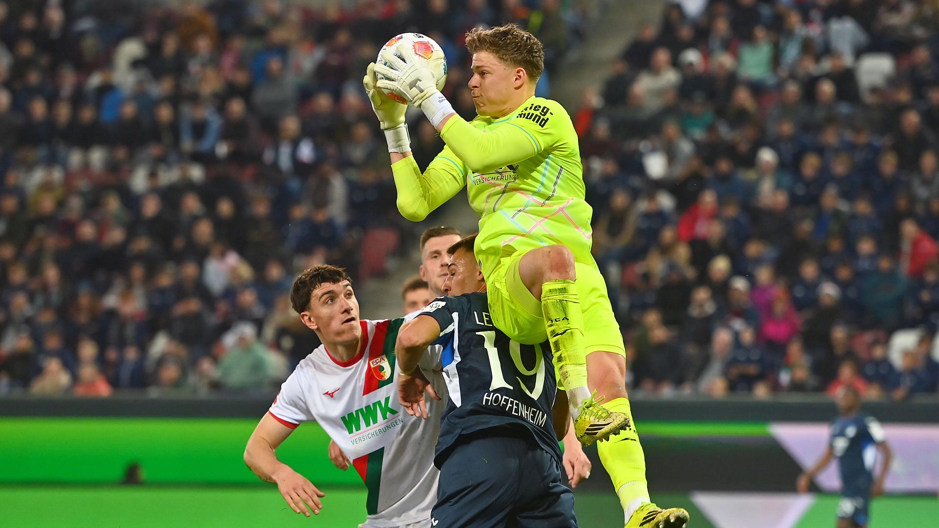 Torwart Finn Dahmen (FC Augsburg) im Zweikampf gegen Tim Lemperle (1899 Hoffenheim) am 10.04.2026 in Augsburg.