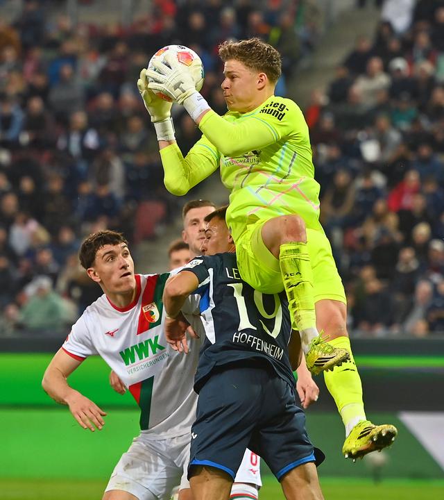 Torwart Finn Dahmen (FC Augsburg) im Zweikampf gegen Tim Lemperle (1899 Hoffenheim) am 10.04.2026 in Augsburg.