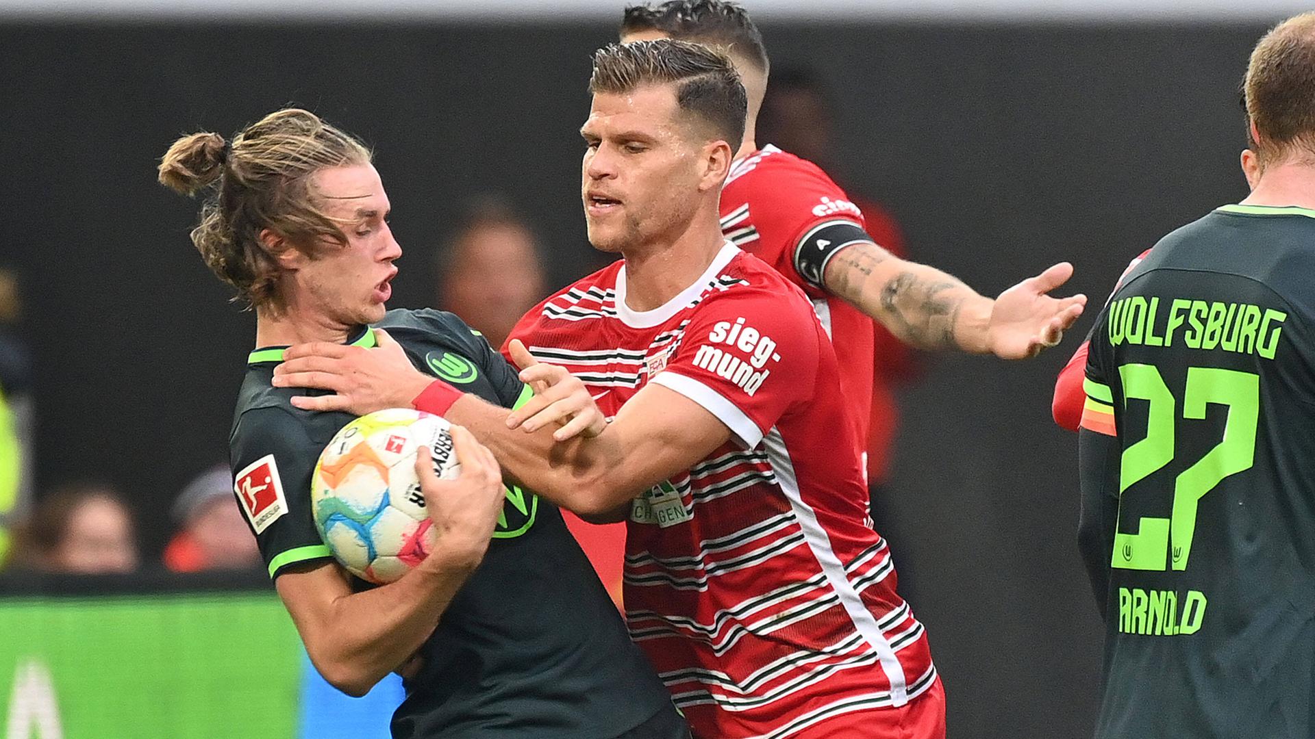 08.10.2022, Augsburg: Florian Niederlechner (FC Augsburg) packt Patrick Wimmer (Wolfsburg) an der Gurgel