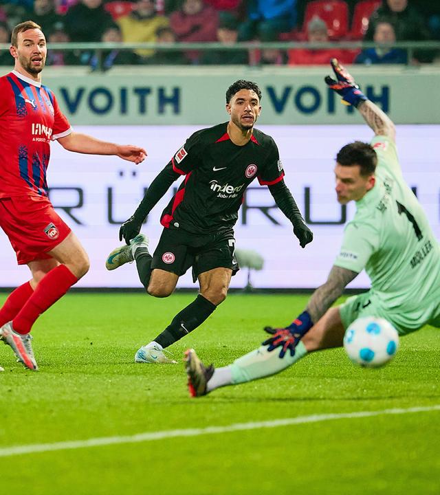 Omar Marmoush von der Eintracht frankfurt schießt das Tor zum 3:0 gegen Torhüter Kevin Müller des 1. FC Heidenheim.