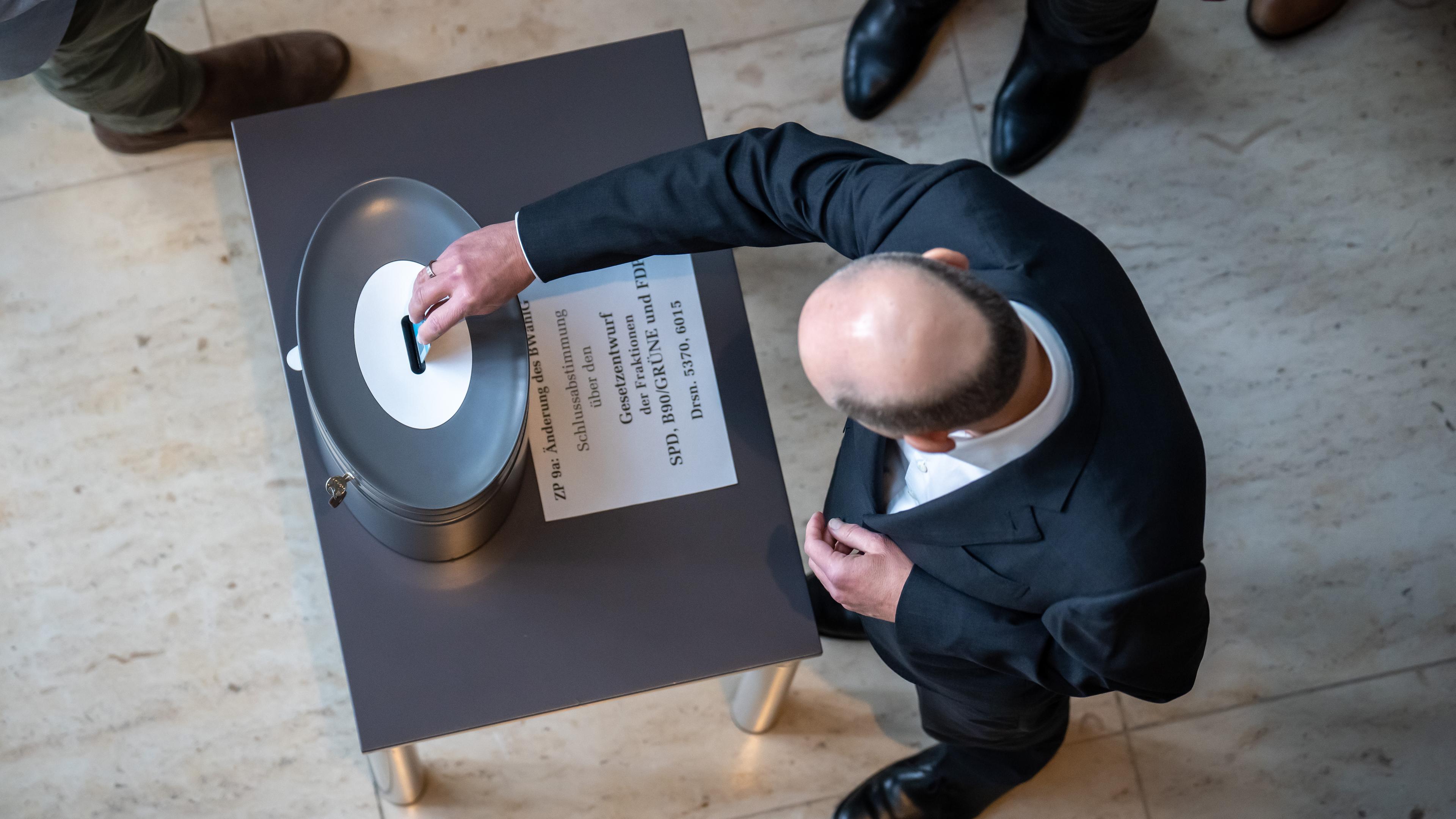 Bundeskanzler Olaf Scholz (SPD), wirft seine Stimmkarte bei der namentlichen Abstimmung im Bundestag