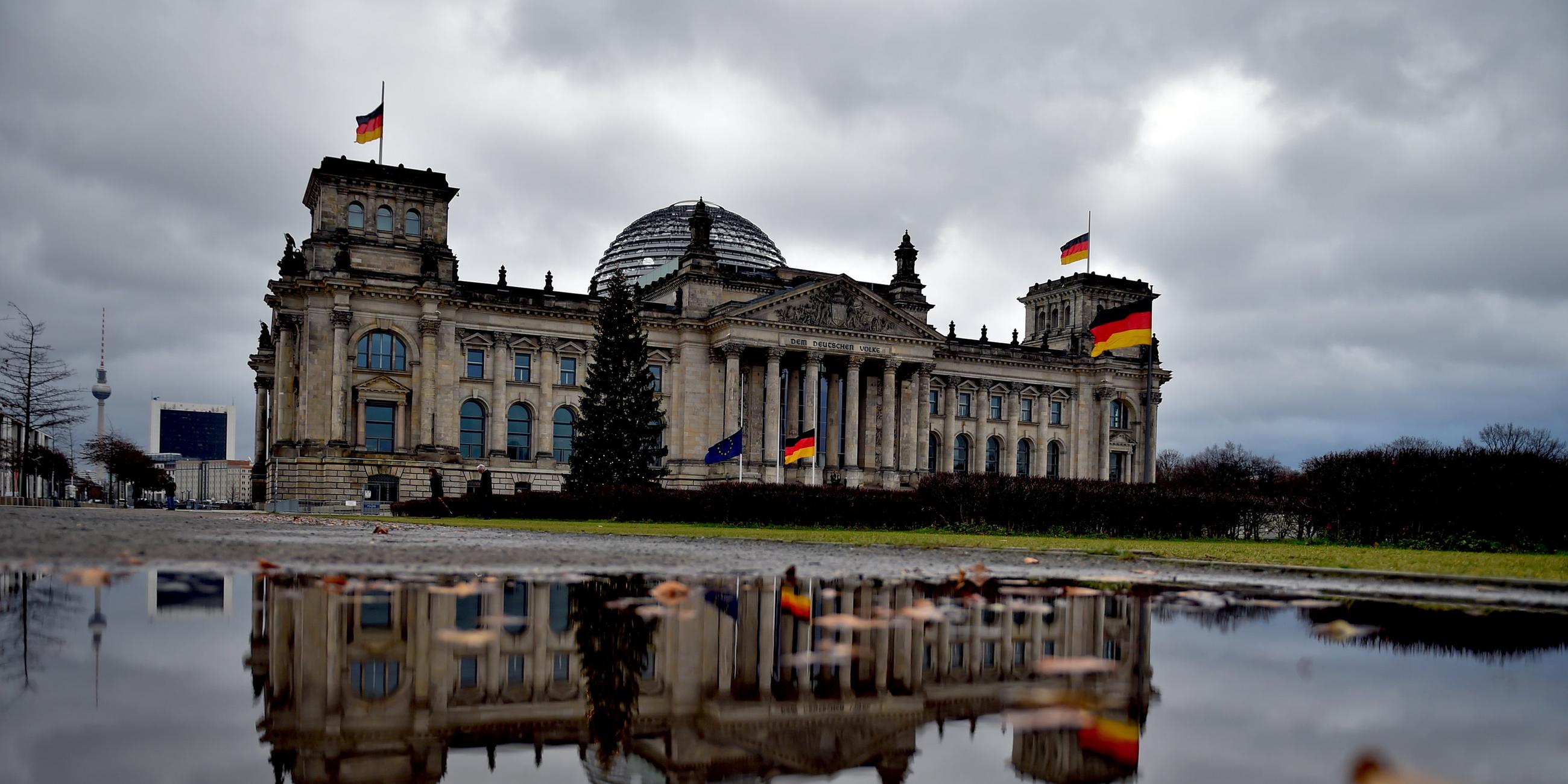 Das Reichstagsgebäude spiegelt sich am 12.12.2017 in Berlin in einer Wasserpfütze wider.