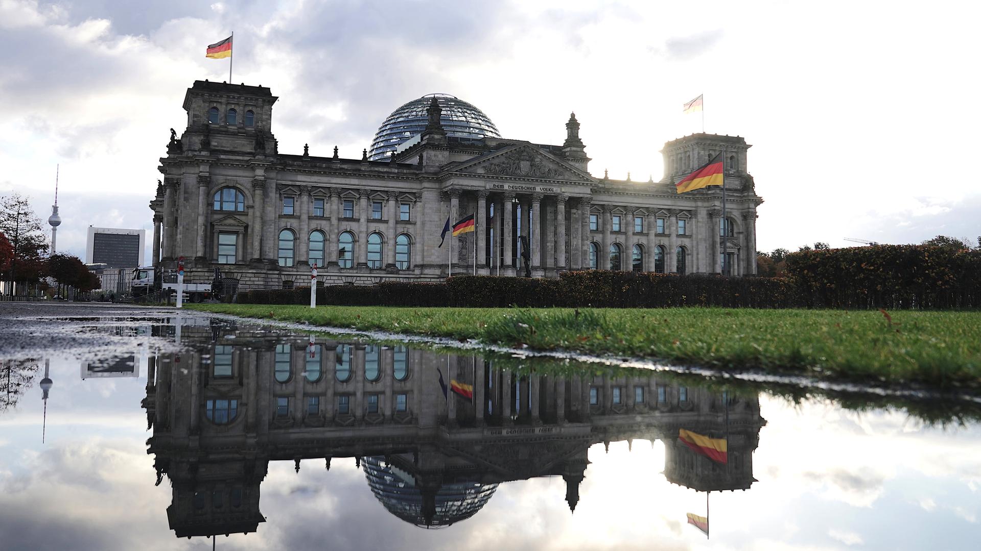Das historische Gebäude des Bundestags spiegelt sich in einem kleinen Teich hinter dem Gebäude.