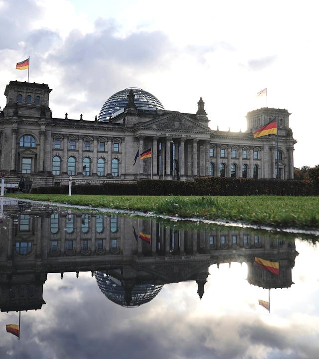 Das historische Gebäude des Bundestags spiegelt sich in einem kleinen Teich hinter dem Gebäude.