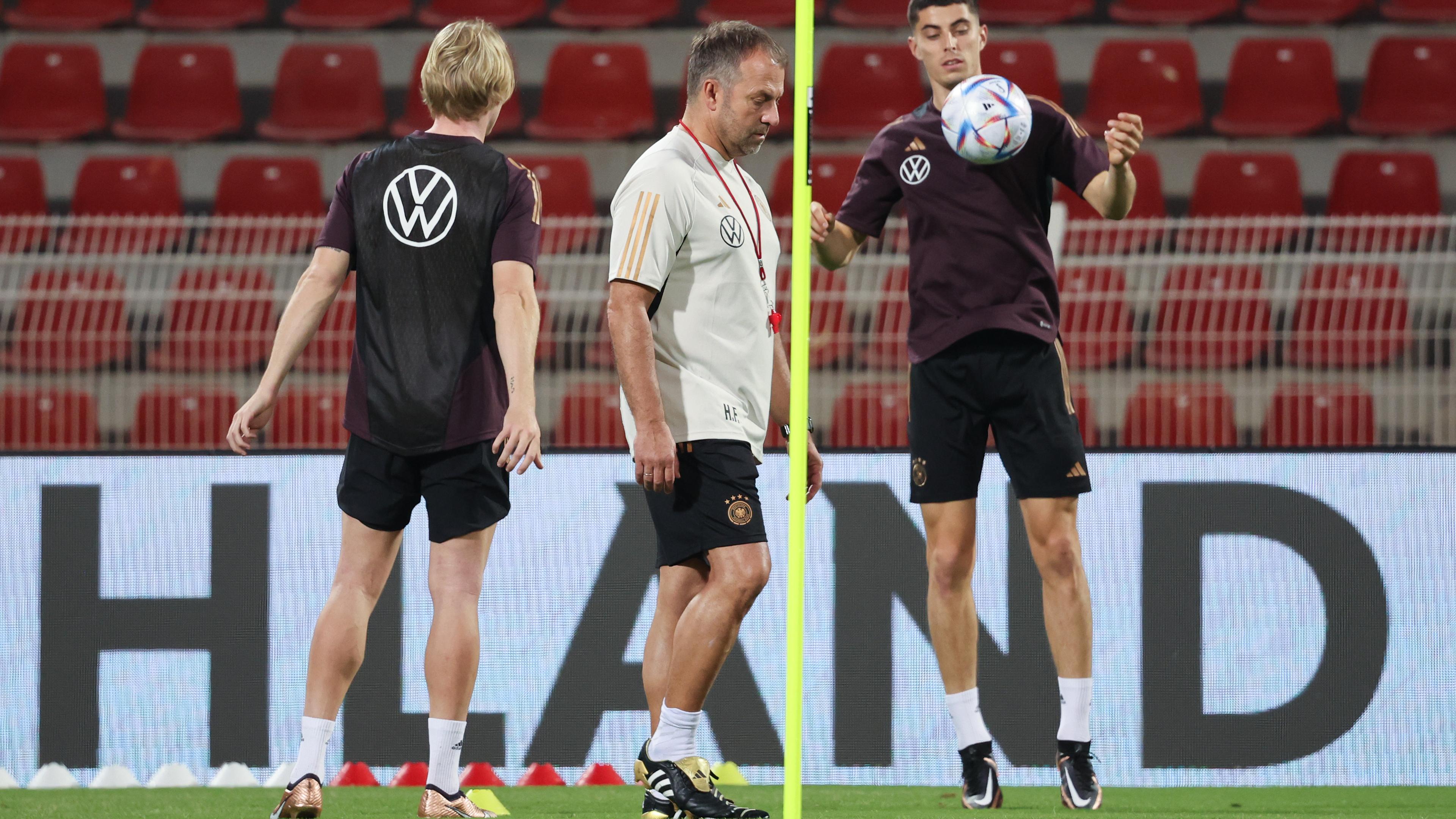 Oman, Maskat: Bundestrainer Hansi Flick (M) leitet das Training, während sich Kai Havertz (r) und Julian Brandt den Ball zuspielen.