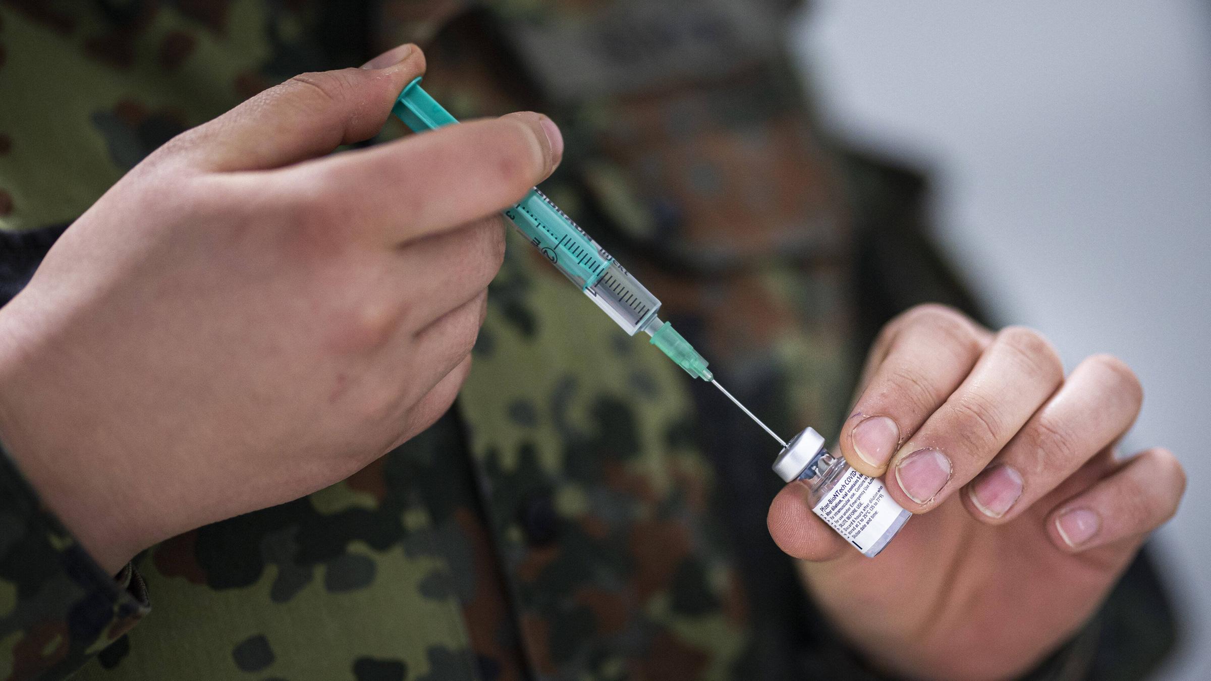 Eine Soldatin zieht eine Spritze mit Corona-Impfstoff auf