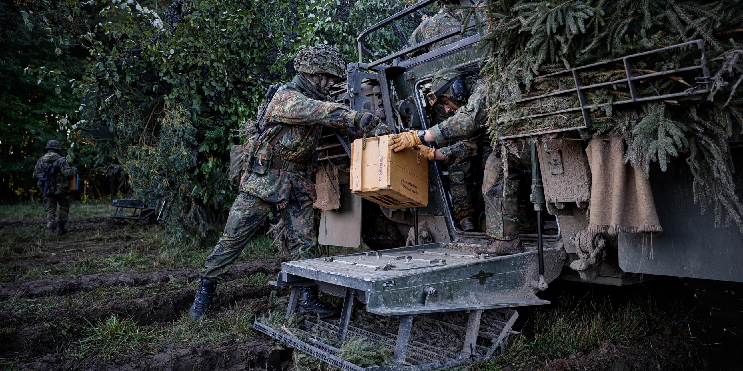 Zwei Soldaten der Bundeswehr sitzen vor einem Puma-Schützenpanzer.