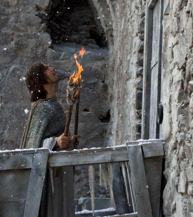 Mann mit Fackel vor Burgtor