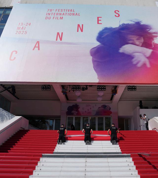 Crewmitglieder verlegen den roten Teppich im Palais des Festivals vor der Eröffnungszeremonie der 78. Internationalen Filmfestspiele in Cannes.