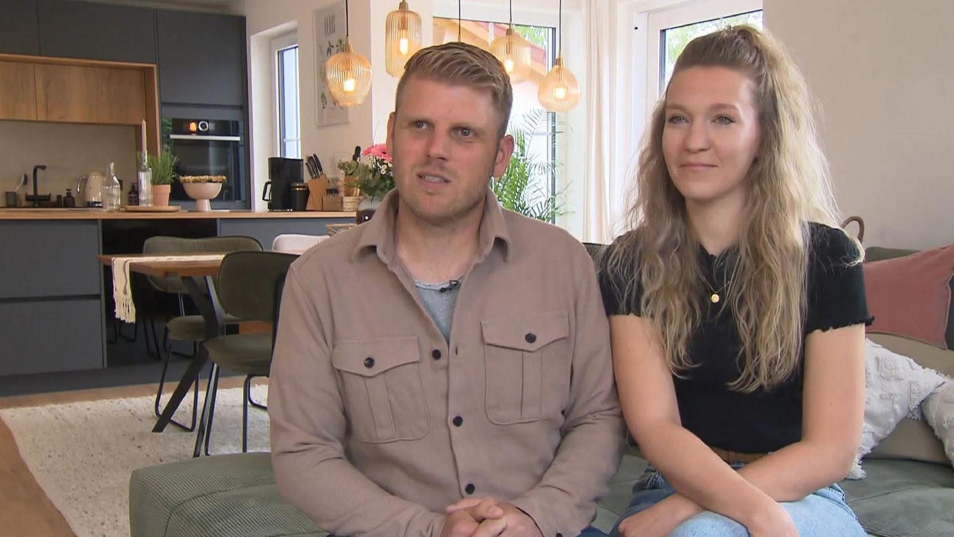 Carina und Johannes Sterner stehen lächend in ihrer Küche und schauen in die Kamera. 