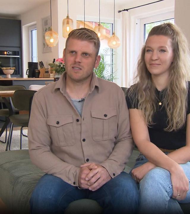 Carina und Johannes Sterner stehen lächend in ihrer Küche und schauen in die Kamera. 