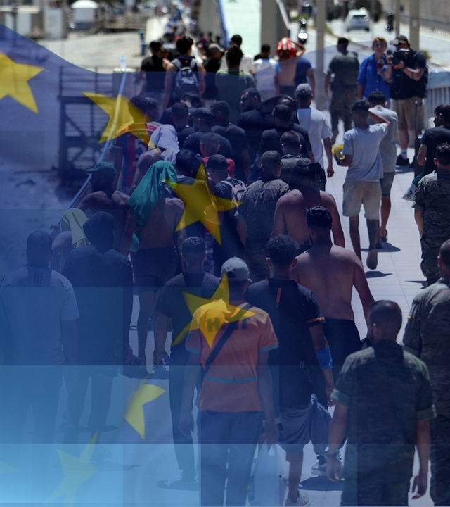 Migranten laufen in Ceuta eine Treppe nach oben. Es ist eine Europaflagge zu sehen. 