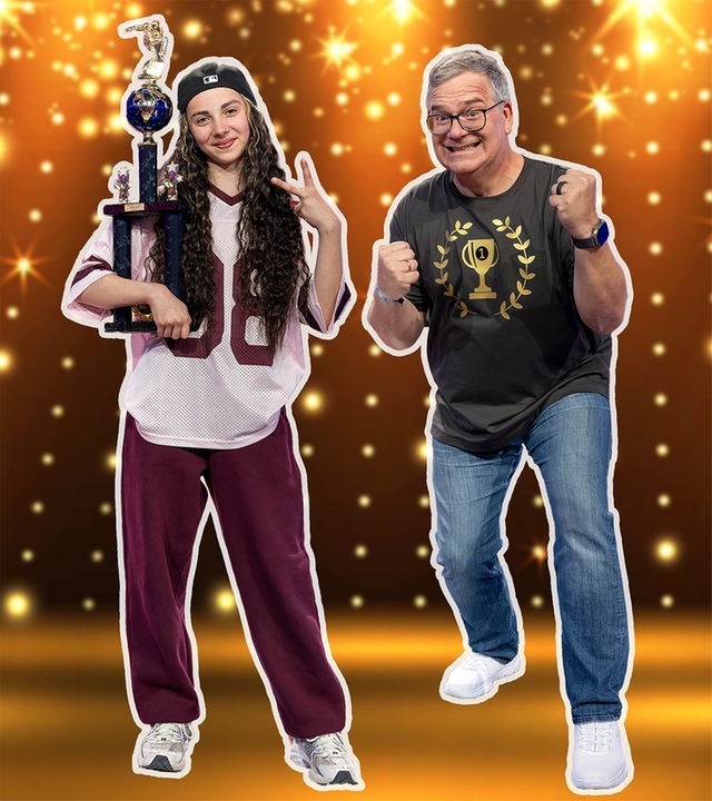Aurelia de Maio präsentiert einen hohen Pokal und blickt selbstbewusst in die Kamera. Elton posiert daneben jubelnd vor einer funkelnden Kulisse.