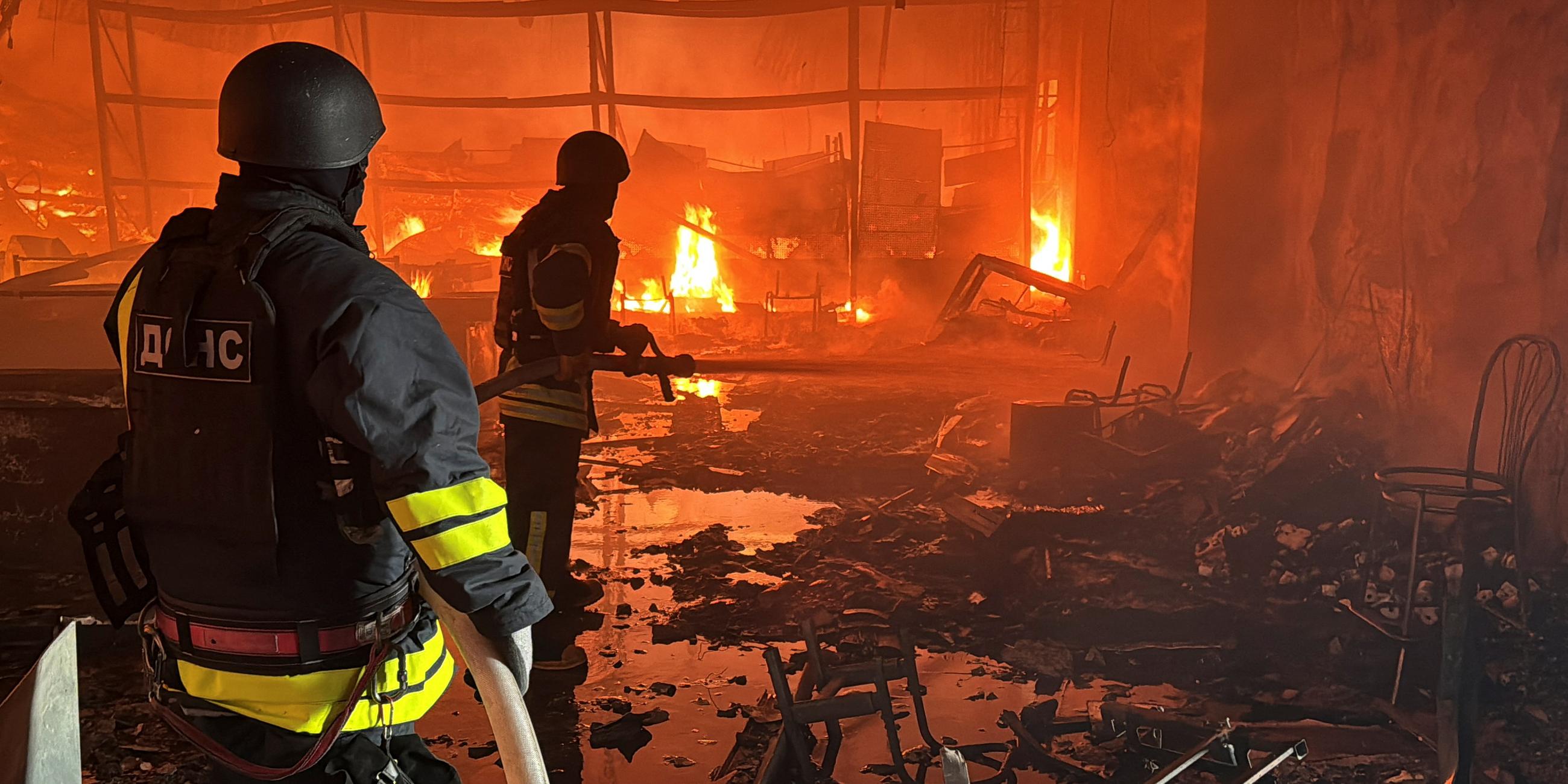 Charkiw nach einer russischen Raketenattacke. Feuerwehrmänner löschen den Brand in einer getroffenen Einkaufsmeile.