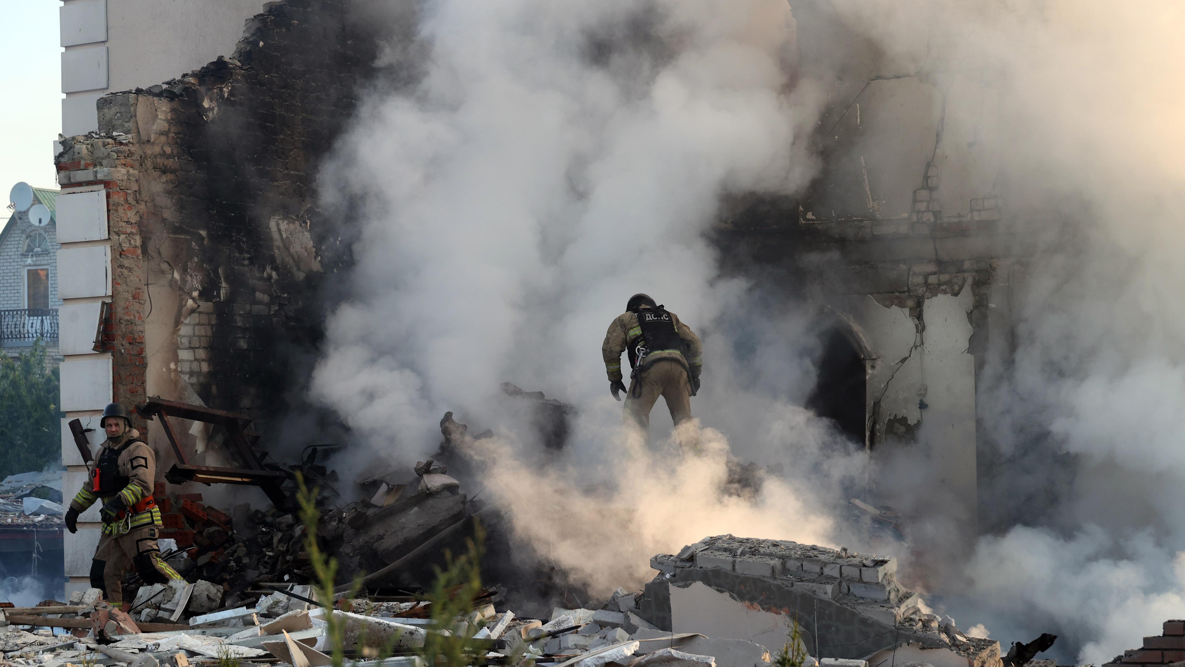 Ein Feuerwehrmann geht durch den Qualm eines brennenden Hauses, nach russischen Beschuss
