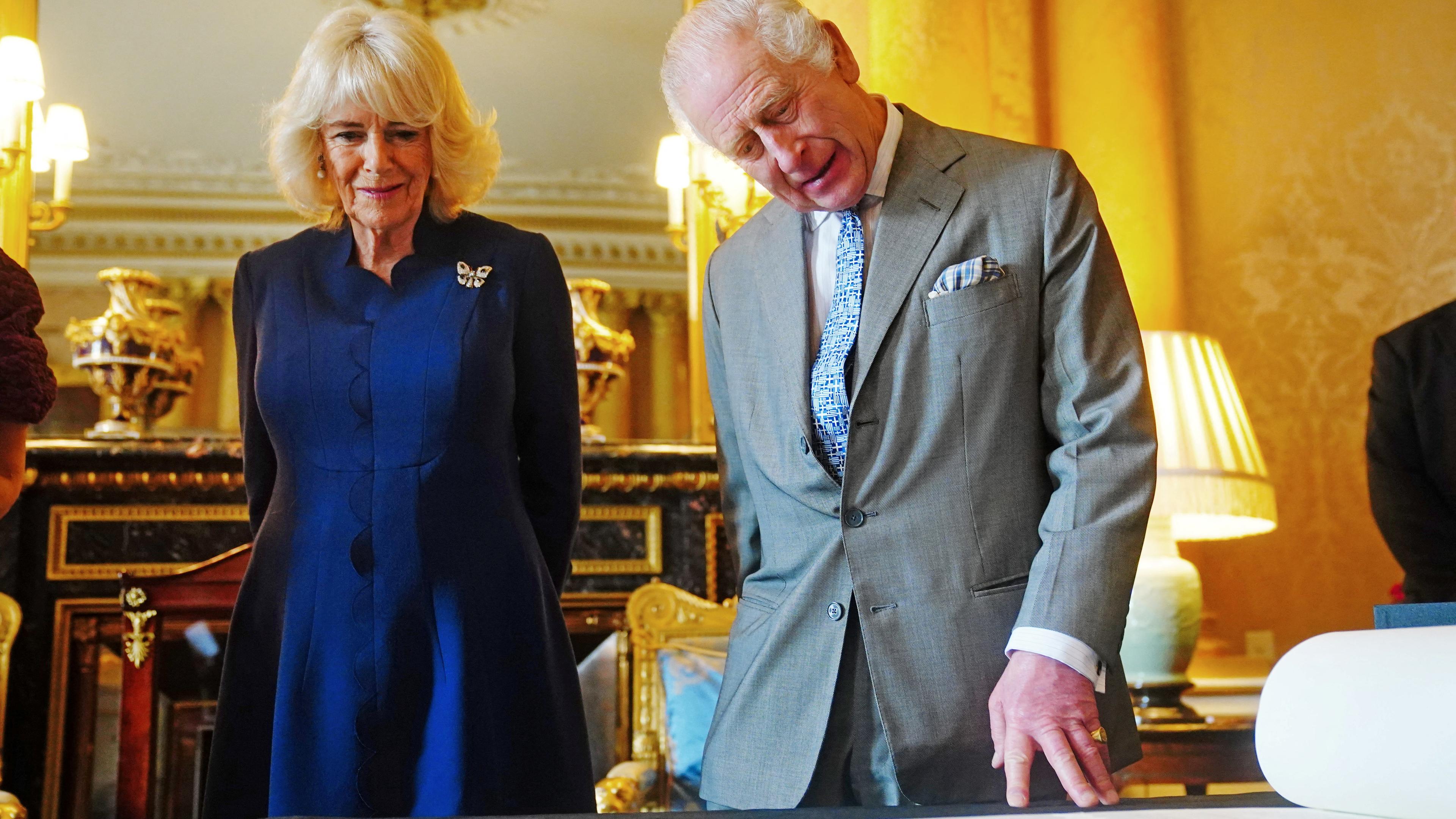 König Charles und Königin Camilla schauen sich die Krönungsrolle an.