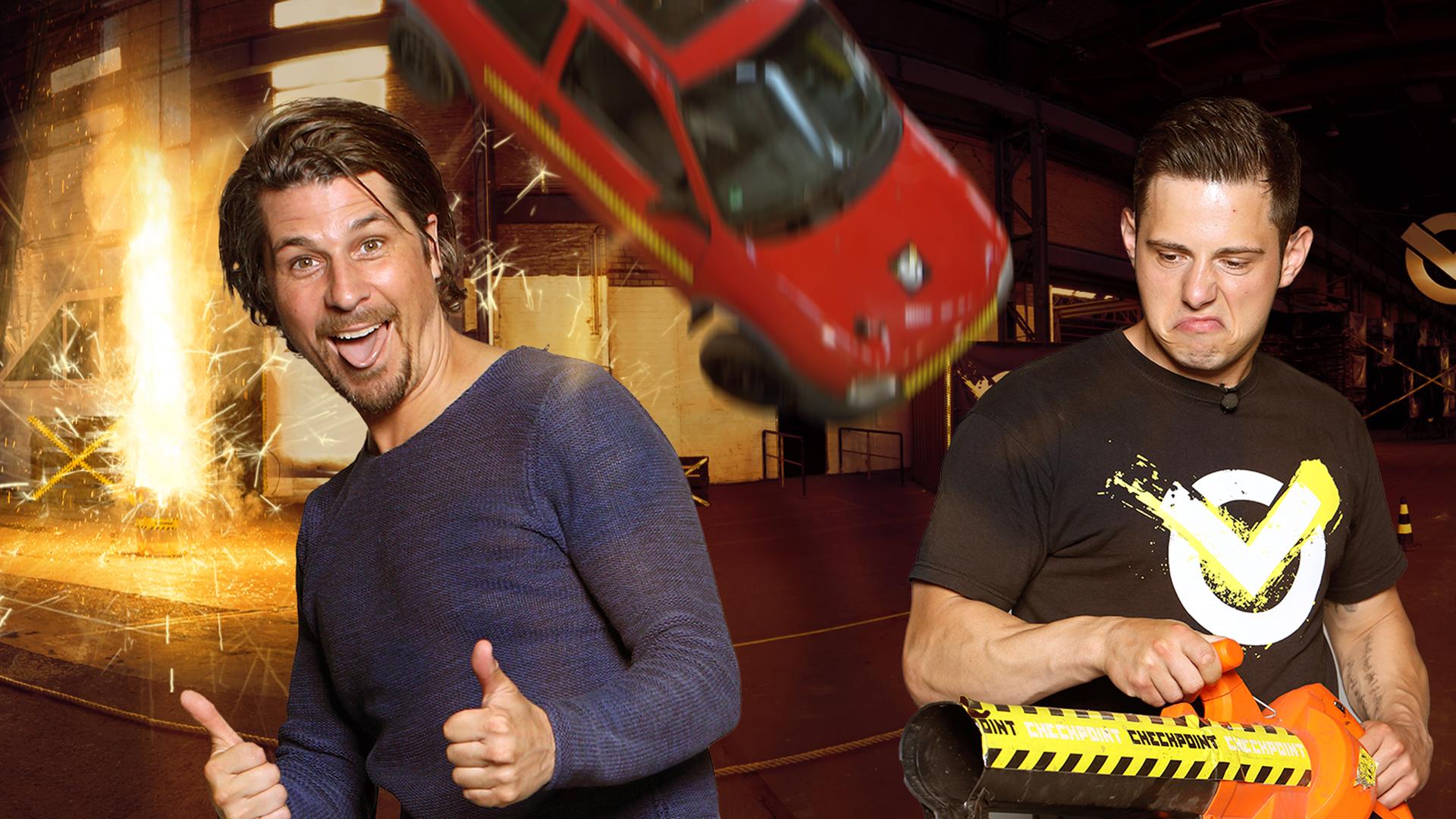 Checkpoint: Der Moderator der Sendung, Tommy Scheel, streckt die Zunge heraus und streckt beide Daumen nach oben. Ein grimmig schauender Junge rechts neben ihm hält eine Art Laubbläser und im Hintergrund stürzt ein Auto von der Decke.