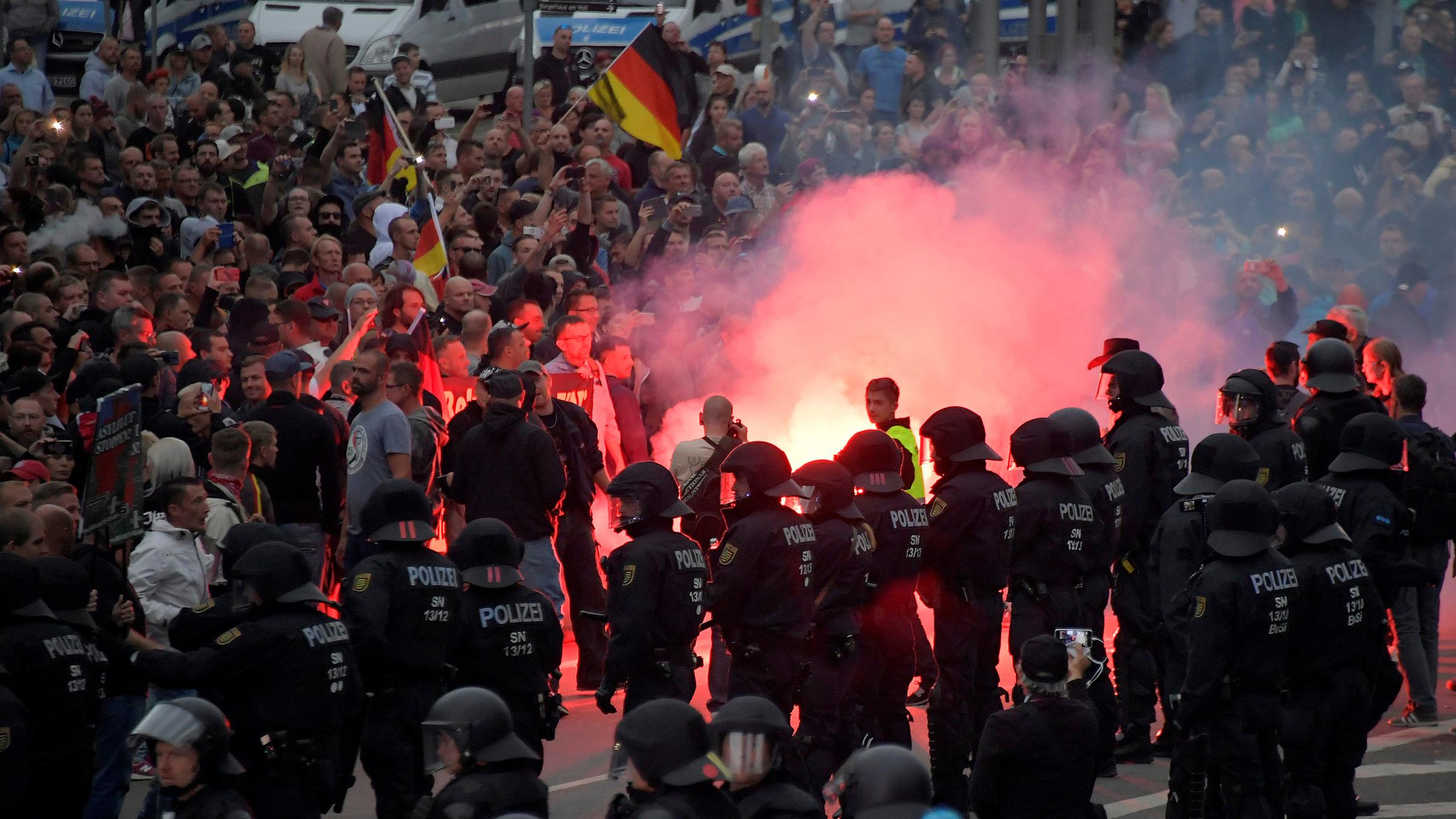 Polizisten stehen vor rechtsgerichteten Demonstranten in Chemnitz