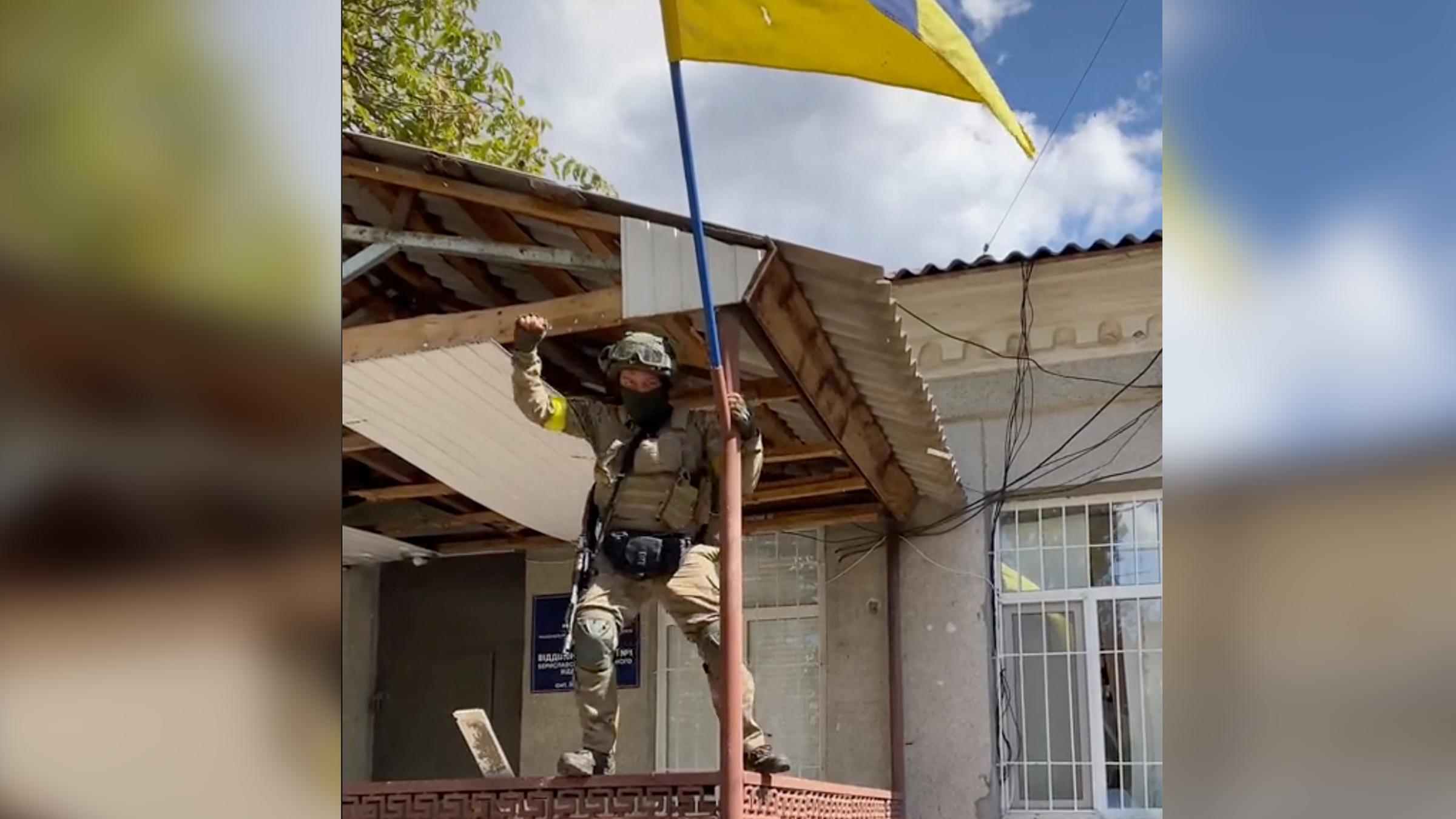 ukrainische Offensive bei Cherson: Ukrainer, der eine Flagge in einem rückeroberten Ort hisst