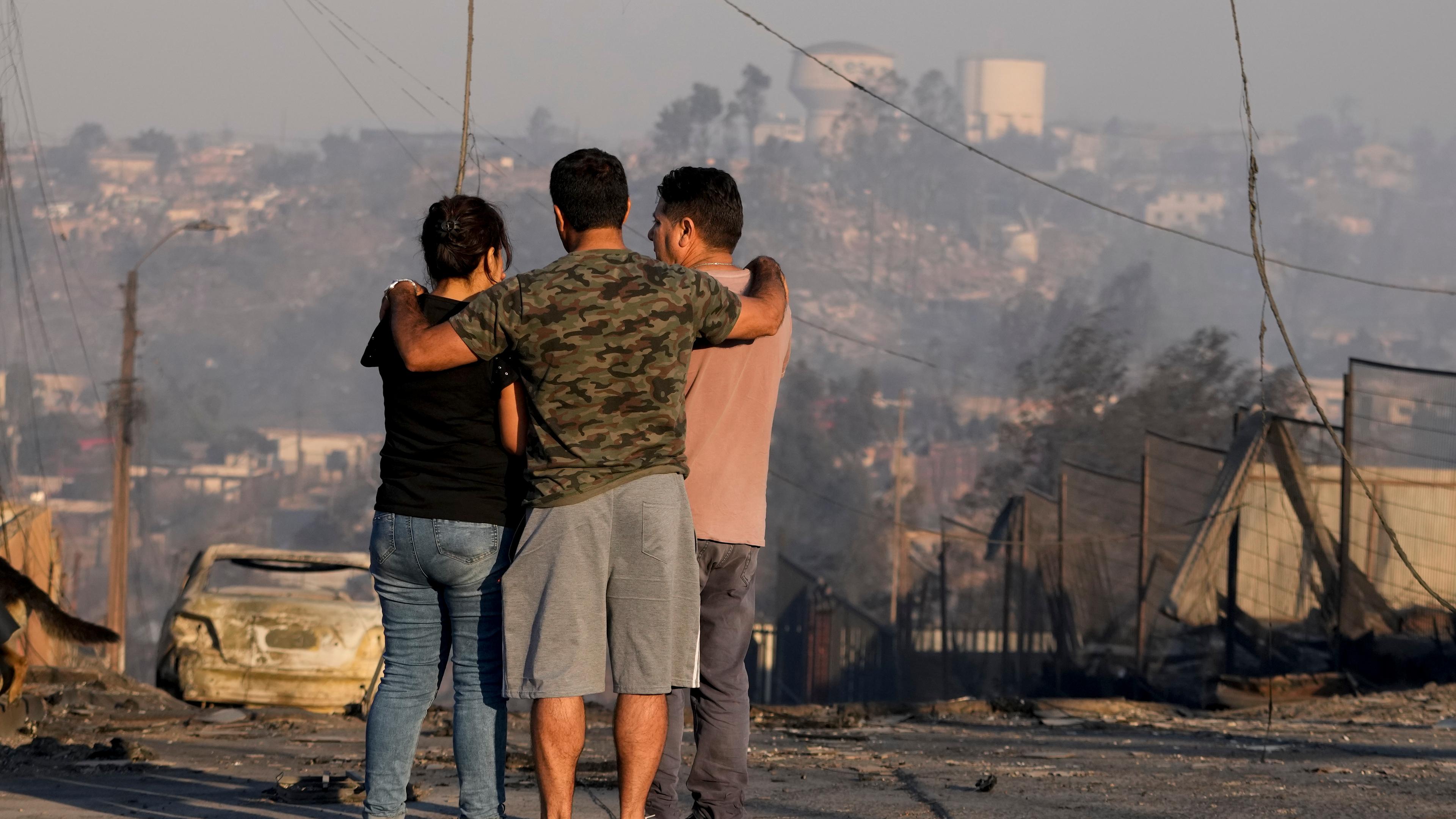 Waldbrände plagen Chile: Einheimische sehen sich ausgebrannte Häuser und andere Trümmer an, nachdem ein Waldbrand ihr Viertel erreicht hat.